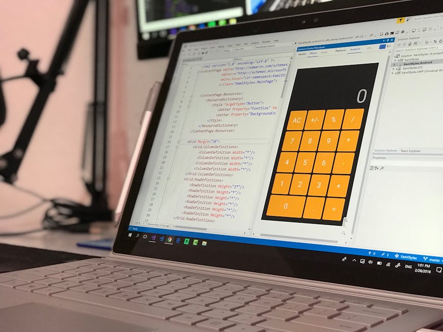Close-up image of a laptop computer on a desk displaying a software development environment with code on the left side and a large orange calculator interface on the right. The code appears to be HTML